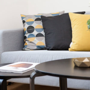Throw Pillows that are multi color circles, all black and all yellow on a couch