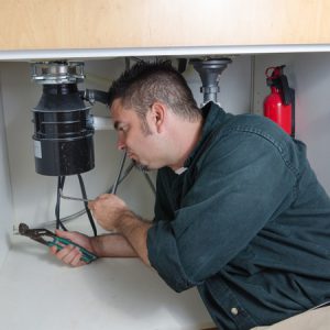 Plumber fixing a garbage disposal